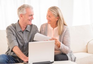 Happy senior couple with laptop paying bills online at home